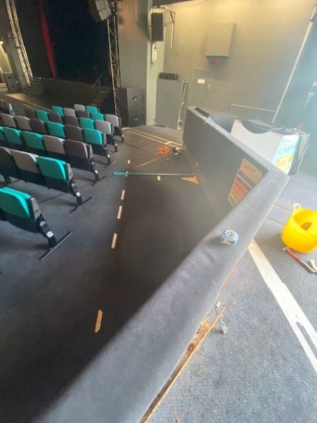 New ramp Empty theatre seating with a view of the stage, scattered props and equipment nearby.